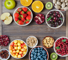 Mix of fresh berries, nuts and fruits. Healthy food contains a lot of vitamins and useful trace elements.Brown wooden background. Copy space.