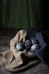 Easter still life in a rustic style. marble eggs in an earthen bowl on a towel on the background of linen fabric. A method for dyeing eggs with a natural dye made from blueberry juice.