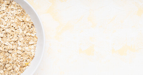 Oat flakes in a white plate on a yellow cement background