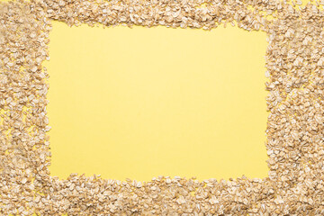 Yellow background with oat flakes frame. View from above. Space for text