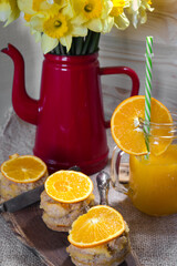 Cozy spring morning atmosphere - fresh narcissus flowers in vintage ceramic pot, delicious homemade orange pie with citrus curd cream and freshly squizzes orange juice