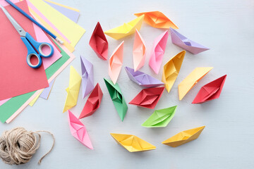many multi-colored boats. View from above. DIY origami boat. Scissors, plain pencil, colored paper. Crafts for children, creativity. Light background.