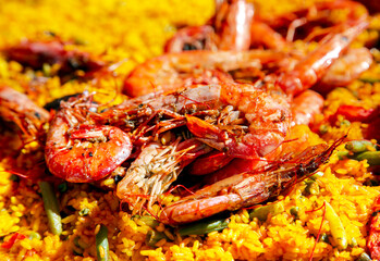 Spanish paella with green beans, large prawns and other seafood cooked in a wok pan on the street.	
