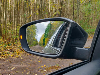 Obraz premium Autumn nature in the rearview mirror. Autumn journey.