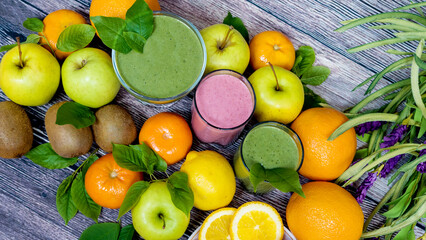 Fresh fruits on a wooden background and three glasses of smoothies. Detox. The right food. View from above