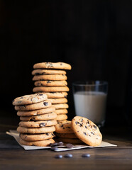 Biscuits with chocolate drops and a glass of milk on a wooden table.