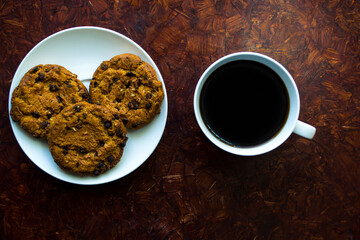 A cup of coffee and a round cookie on a saucer, morning breakfast.