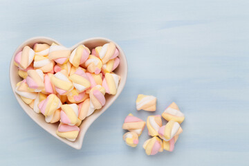 Marshmallows on blue background with copyspace. Flat lay or top view. Background or texture of colorful mini marshmallows.
