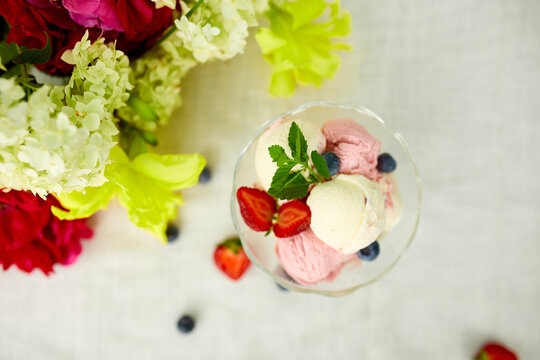 Tasty Ice cream and fresh blueberries, strawberry in the bowl, presented with flower