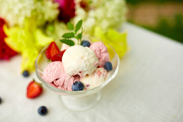 Tasty Ice cream and fresh blueberries, strawberry in the bowl, presented with flower