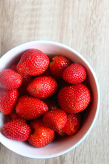 Bowl of fresh strawberries on a table. Flat lay.