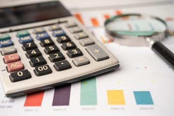 Magnifying glass and calculator on charts graphs paper.  