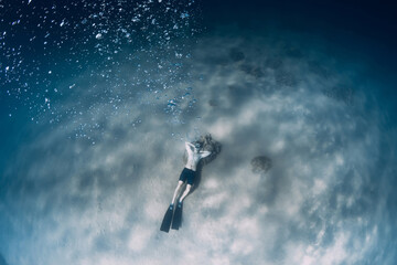 Naklejka na ściany i meble Free diver make bubbles in sea. Sporty man freediver in sea