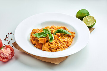 Classic Italian pasta (spaghetti) with seafood, salmon and red sauce in a white plate on a white plate