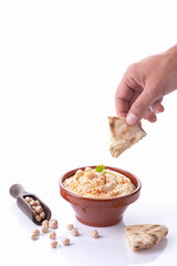 Hand dipping pita bread in hummus isolated on white background with copy space. Vertical format.