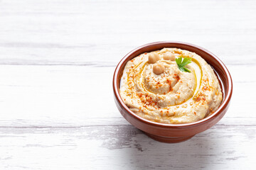 Bowl of homemade hummus isolated on light background with copyspace.