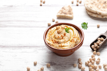 Bowl of homemade hummus on light background with copyspace. - obrazy, fototapety, plakaty