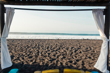 Sunrise on empty volcanic sand beach - View of the sea from a cabin in Port of San Jose in...