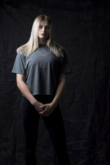 Portrait of a young beautiful blonde girl in a sports uniform on a dark background.