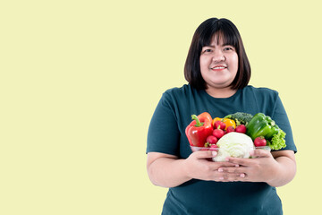 Portrait images of Asian attractive fat woman holding glass bowl  contains fruit and fresh vegetables On yellow background, to woman with health food and weight loss concept.