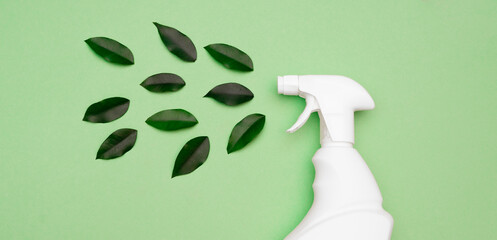 Eco style cleaning concept. White bottle Spray for daily spring cleaning sprays green leaves on a green background close-up. Environmentally friendly cleaning products. top view. Flat lay. copy space