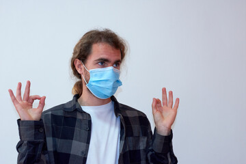 A Spanish young bearded male covering his face with a protective facemask