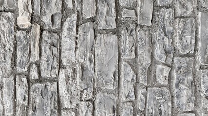Old stone wall close up for background.  Texture of old gray stone.  Wallpaper, copy space.  Monochrome.