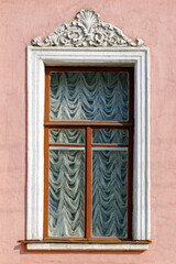 Rectangular window with a bas-relief on the background of a pink stucco wall. From the windows of St. Petersburg series.