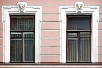 Fototapeta na wymiar Two rectangular windows with white bas-relief on the background of a pink stucco wall. From the windows of St. Petersburg series.