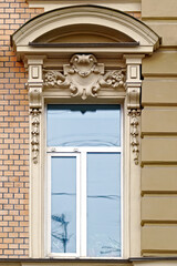 Rectangular window with arched visor stucco on the background of the beige wall. From the windows of St. Petersburg series.