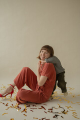 Mom in a red dress is sitting on the floor with her son and having fun. holiday. Body positive