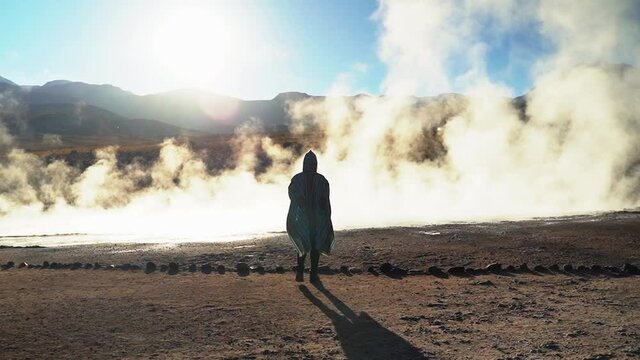 BACK WOMAN WHEN SUN IS RISING IN THE ATACAMA DESERT WITH PONCHO