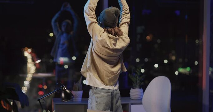 Positive handsome young creative desinger caucasian man finishing computer project via laptop standing at table strecthing back leaving the office.