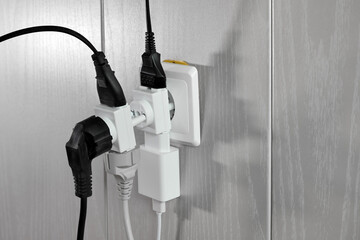 Multiple plugs in wall electrical outlet is dangerous overload, close-up