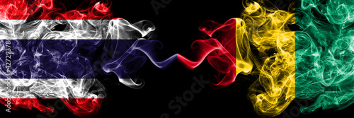 Thailand, Thai vs Guinea smoky mystic flags placed side by side. Thick colored silky abstract smokes flags.