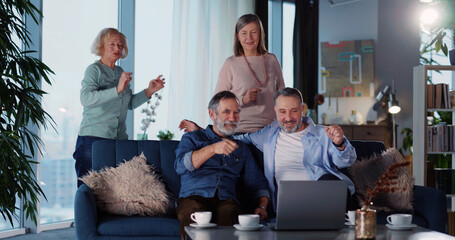 Cheeful old friends gathering at home watching Tv programs and communicating. Friendship. Elderly pensioners. Entertainment.