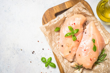 Chicken fillet with spices and herbs at white table.