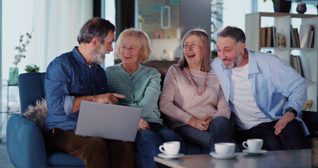 Couples of caucasian men and wopmen old friends socializing gathering in living room playing to deliver food service delivery online using laptop.