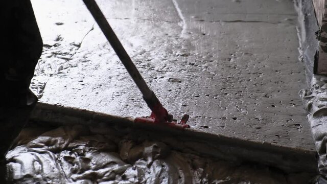 Worker man align the level of liquid monolithic foam concrete for warming and sound insulation of house.