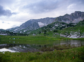 Naklejka na ściany i meble panoramic view of the mountain lake with tourist tents a cloudy summer day. Adygea, Russia.