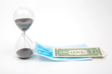 hourglass, dollar and medical mask on a white background. time and protection from the virus. financial losses due to the virus epidemic. business in medicine