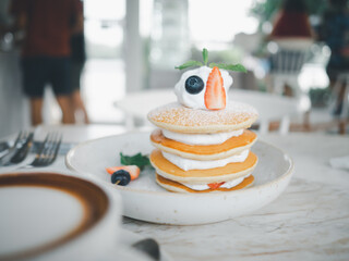 Pancake cream blueberry yogurt delicious on topping with berries and strawberry blur front coffee, Sweet homemade stack  for breakfast pancakes in cafe background. Selective focus on Pancake.