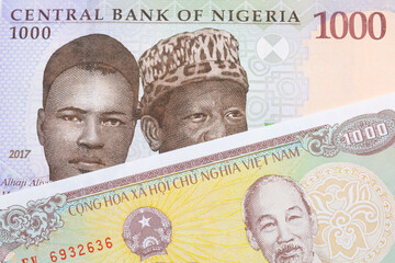 A macro image of a blue, purple and green one thousand  naira note from Nigeria paired up with a yellow one thousand dong bill from Vietnam.  Shot close up in macro.