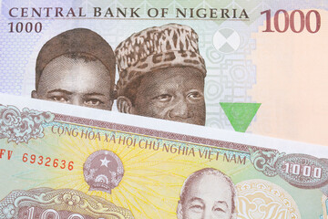 A macro image of a blue, purple and green one thousand  naira note from Nigeria paired up with a yellow one thousand dong bill from Vietnam.  Shot close up in macro.