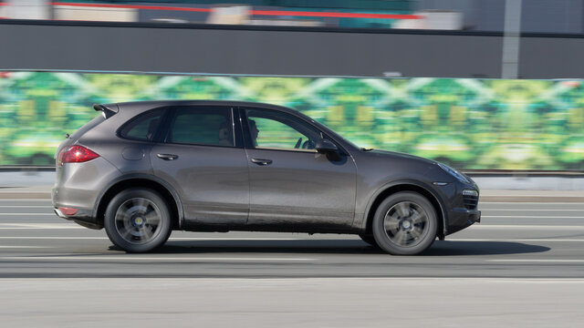 Gray Porsche Cayenne car moving on the street. Compliance with speed limits on road concept. Dynamic exterior image
