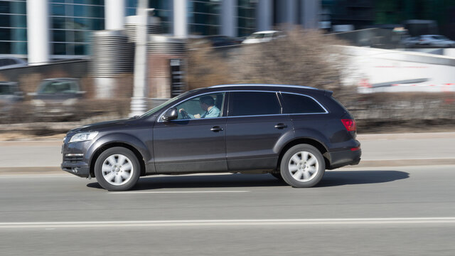 Audi Q7 SUV vehicle on the city road. Fast moving dark gray car on Moscow streets. Accelerating with low-emission. Compliance with speed limits on the road