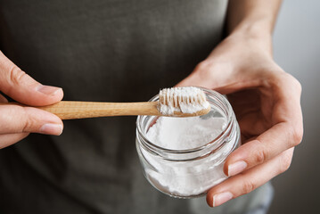 Woman holds bamboo toothbrush and soda powder in her hands