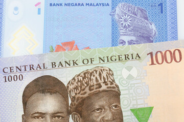 A macro image of a blue, purple and green one thousand  naira note from Nigeria paired up with a blue, plastic one ringgit bank note from Malaysia.  Shot close up in macro.