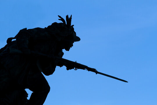 Detail of the bronze sculptural group on the Janiculum Hill, soldier of the Bersaglieri weapon holding a rifle, backlit image and blue sky