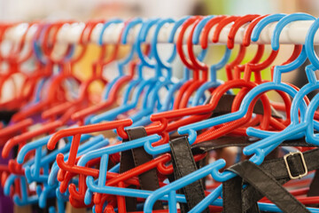 Many plastic colorful hangers on clothes rail. Store concept, sale, design, empty hanger